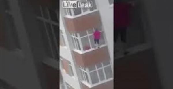 امرأة متهورة تتسلق سور شرفتها لتنظيف الزجاج الخارجي (فيديو)