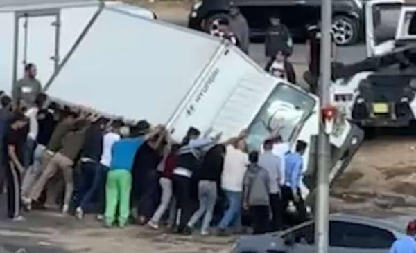 مجموعة من الشباب يرفعون شاحنة بعد انقلابها(فيديو)