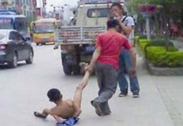 والد صيني يعري ابنه المراهق ويجرجره في الشارع
