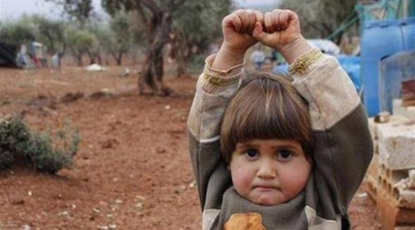 صورة: طفلة سورية ترفع يديها مستسلمة للكاميرا