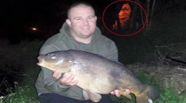شبح مخيف يظهر في خلفية صورة لصياد مع سمكته